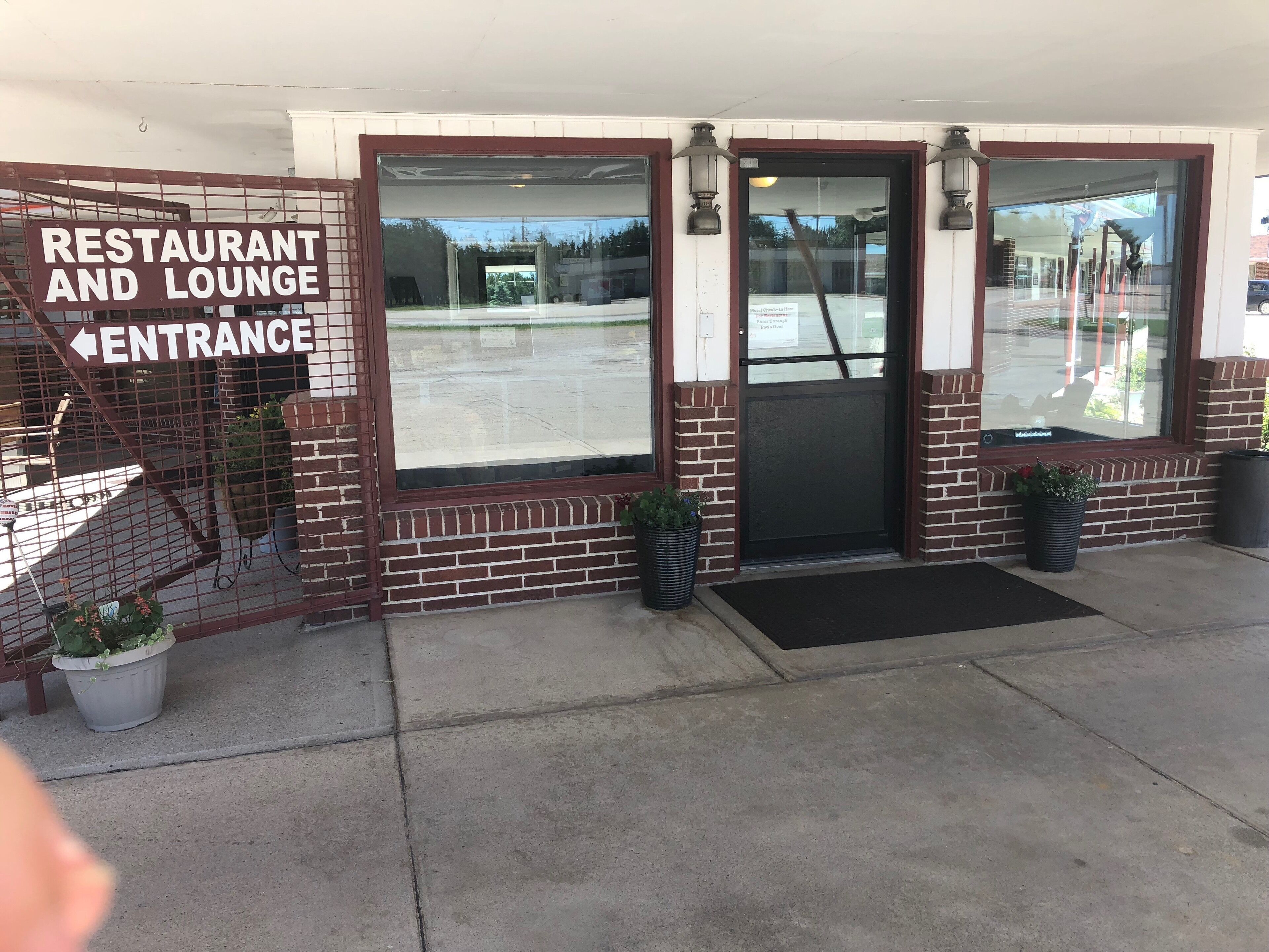 L’entrée d’un restaurant et d’un salon, avec une façade en briques, de grandes fenêtres et une porte noire.