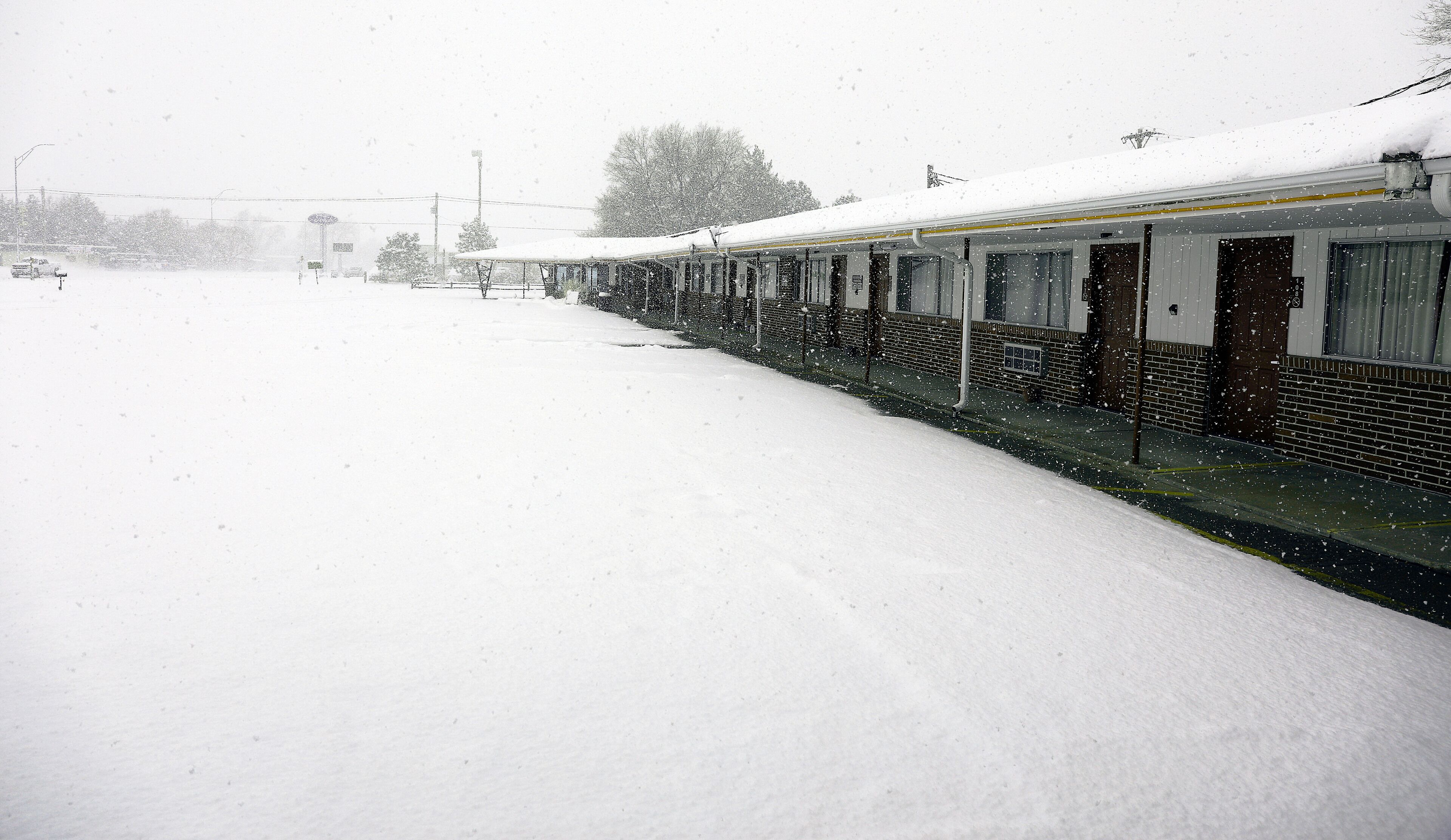 A snow-covered train station platform with a train on the right side.