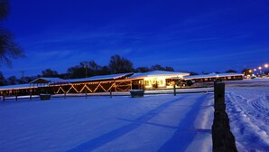 A snow-covered building with a covered outdoor area and a parking lot. - Raine Motel (Valentine)