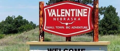 A welcome sign for Valentine, Nebraska, with a road in the foreground.
