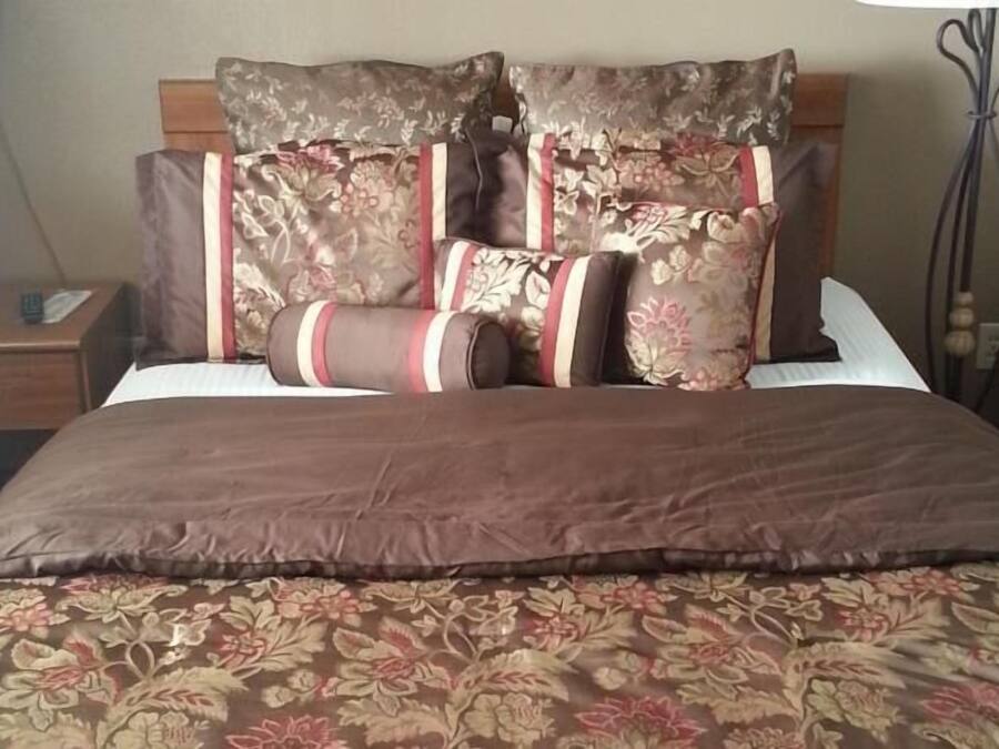 A neatly made bed with floral-patterned bedding and multiple pillows.