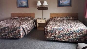Camera d'albergo con due letti, un comodino, due lampade e una sedia.