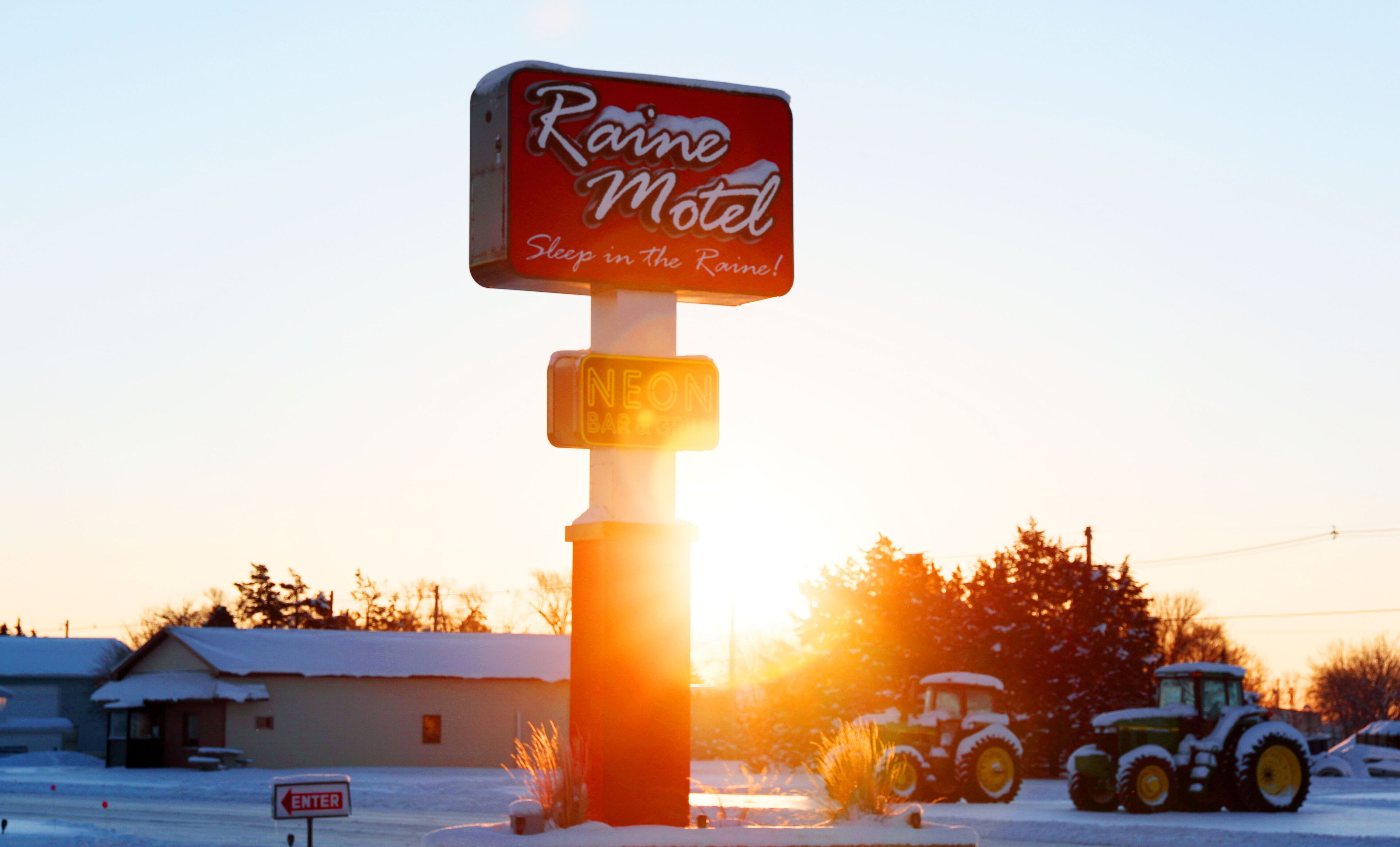 Señal de motel con el texto 'Raine Motel' y 'Duerme bajo la lluvia'.
