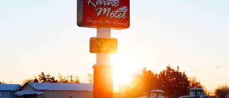 Señal de motel con el texto 'Raine Motel' y 'Duerme bajo la lluvia'.