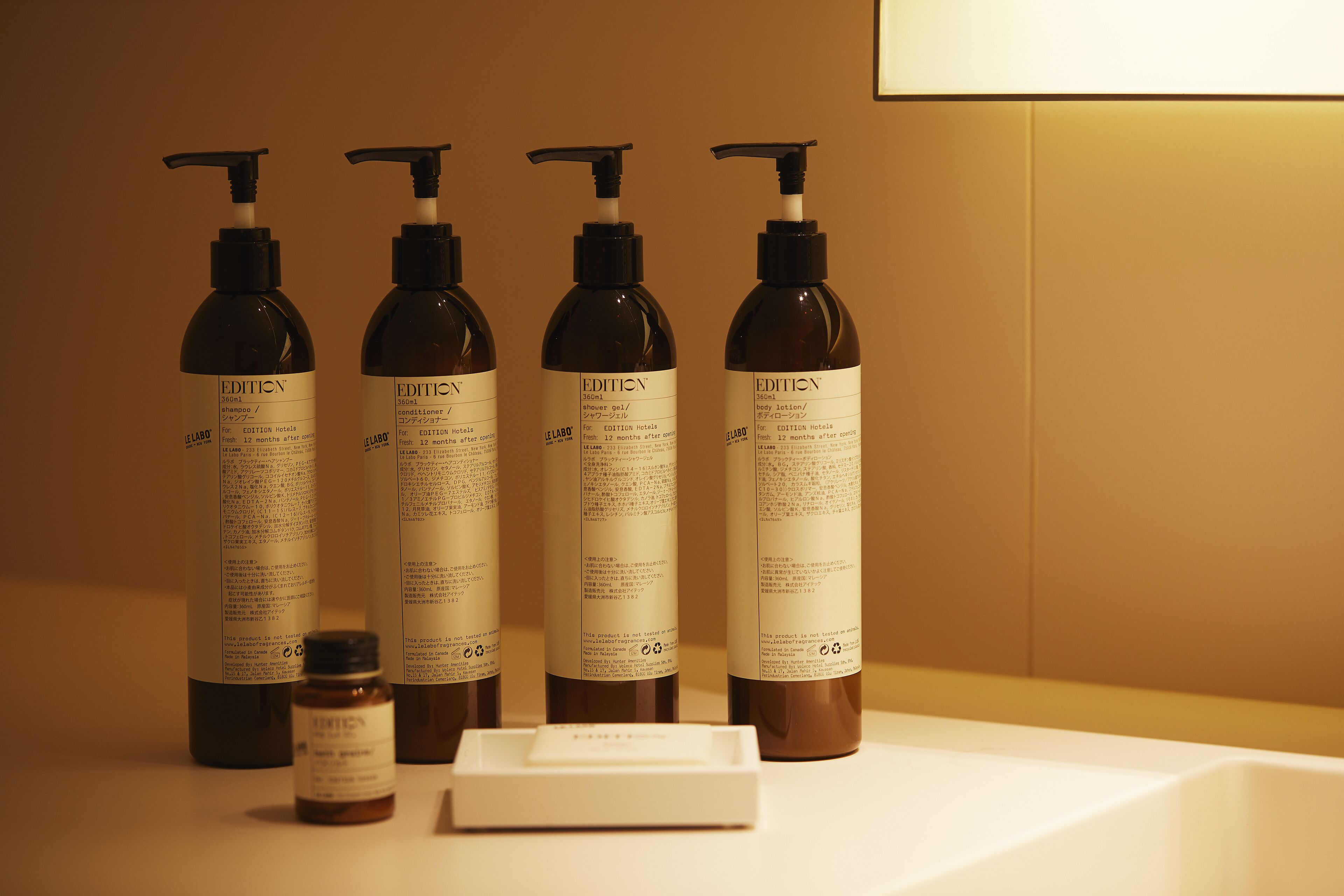 A row of brown bottles with pump dispensers, likely containing hotel amenities, on a white surface.