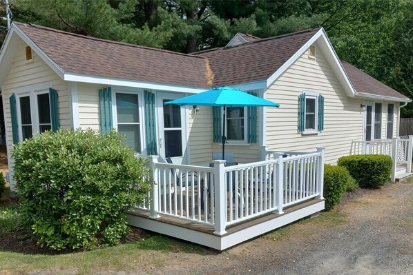 A single-story house with a covered porch, a small deck, and a well-maintained lawn.