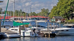 Ein Yachthafen mit mehreren vertäuten Booten, ein kleines Gebäude mit rotem Dach und ein grüner Baldachin über einem Boot.