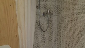A small, enclosed shower area with a tiled wall, a showerhead, and a curtain. - Nido del Corso apartment (Pontedera)