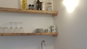 A small kitchen with a wooden countertop, a sink, and a window above the counter. There are shelves above the counter holding various items. - Nido del Corso apartment (Pontedera)