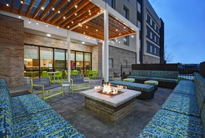 Un patio al aire libre con asientos, una chimenea y luces colgantes.
