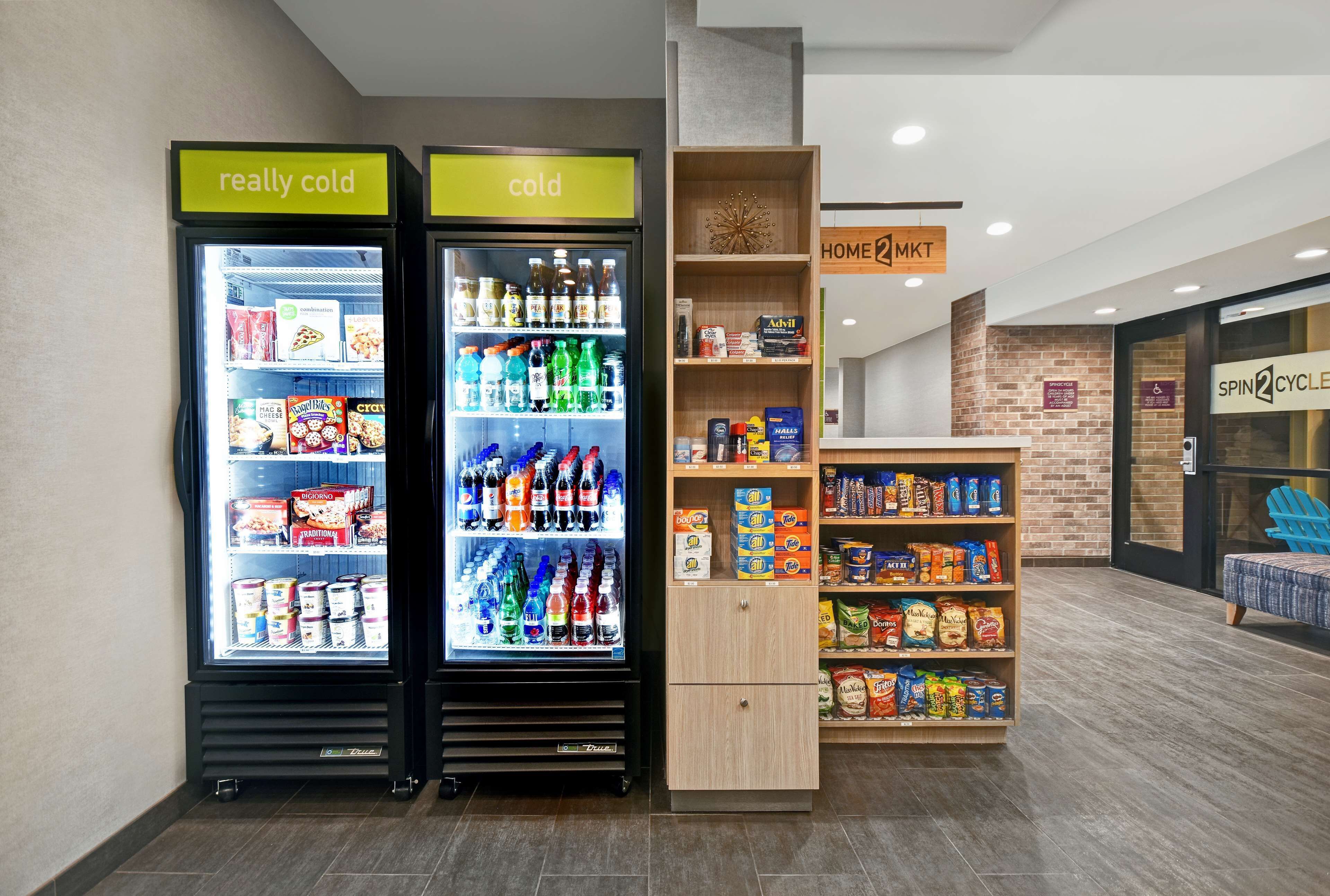 Dos dispensadores de bebidas refrigeradas, uno etiquetado como "muy frío" y otro como "frío", con estantes llenos de diversas bebidas y aperitivos.