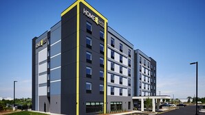 A modern hotel building with a prominent "HOME2 SUITES BY HILTON" sign, multiple floors, and a parking lot with marked spaces. - Home2 Suites by Hilton Liberty NE Kansas City (Liberty)