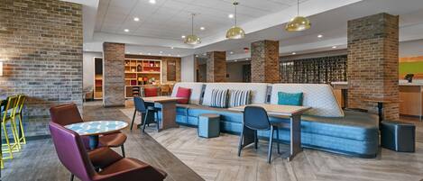 A modern lobby with a seating area, a coffee station, and a reception desk.