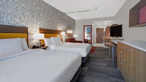 A hotel room with two beds, a desk, a TV, and a bathroom visible through an open door. - Home2 Suites by Hilton Liberty NE Kansas City (Liberty)