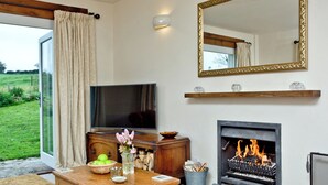 A living room with a fireplace, a television, and a large mirror. - 3 bedroom accommodation in Cheriton, near Lynton (Cheriton, near Lynton)