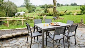 An outdoor patio with a stone table and chairs, surrounded by a rustic fence and greenery. - 3 bedroom accommodation in Cheriton, near Lynton (Cheriton, near Lynton)