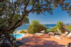 A pool area with lounge chairs and a view of the sea. - Villa near the sea with private pool: Villa Li Cuncheddi (Olbia)