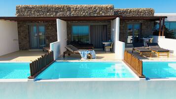 A poolside area with lounge chairs, a table, and a covered seating area.