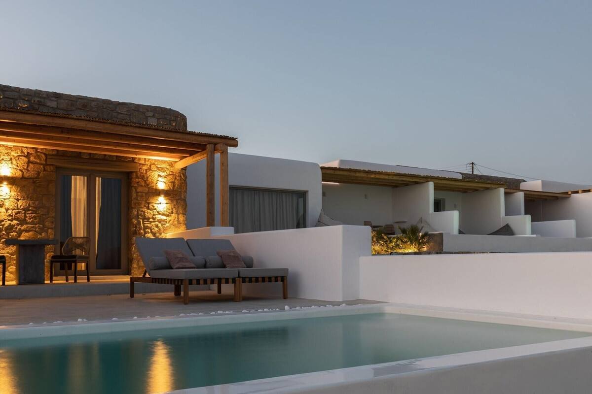 Ein moderner Poolbereich mit Steinmauer, Liegestuhl und kleinem Tisch.