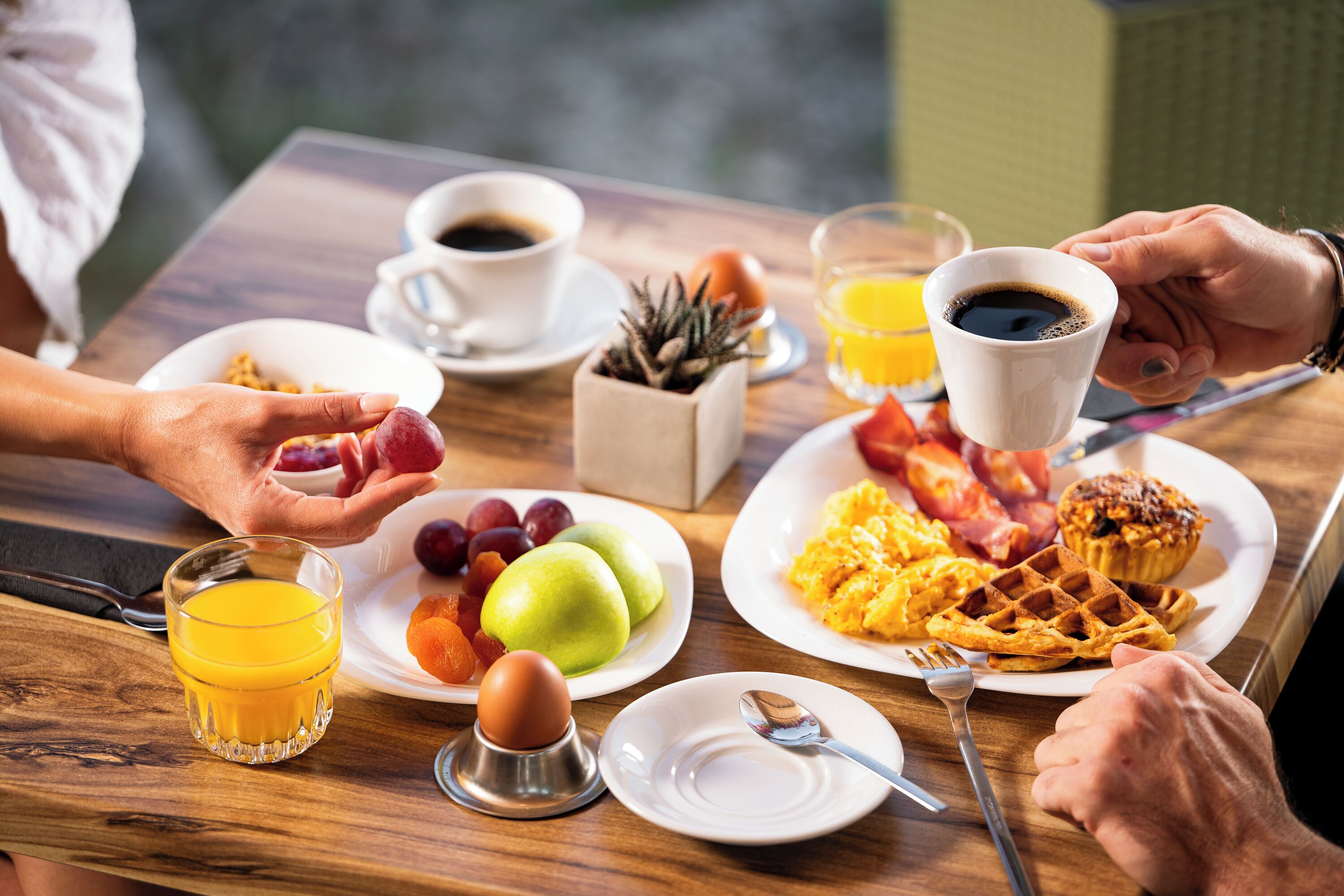 Una mesa de desayuno con platos de comida, una taza de café y un vaso de jugo de naranja.