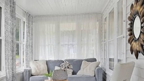 Una sala moderna con un sofá gris, un sillón blanco y una mesa de centro.