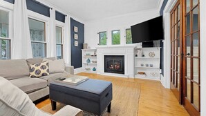 Una sala de estar con chimenea, sofá, mesa de centro y televisor.