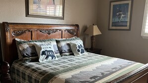Een slaapkamer met een houten bed, een geruite sprei en een hoofdbord met ingewikkelde gravures.