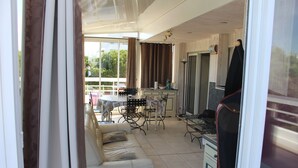 A living room with a sofa, a dining table, and chairs. There is a kitchen area with a refrigerator and a microwave. - Loc Apartment Ben T3 - 6 to 8 people in La Grande Motte (LA GRANDE MOTTE)
