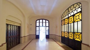 A hallway with a large arched doorway, a glass door with a geometric pattern, and a marble floor. - A View of Rome (Rome)