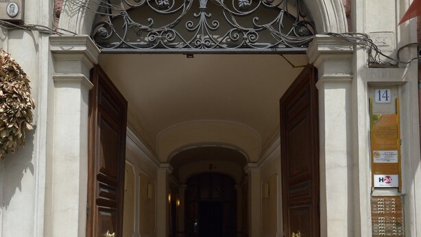 An ornate entrance with a wrought iron gate, a balcony with flowers, and a mailbox. - A View of Rome (Rome)