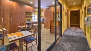 A modern kitchen with wooden cabinets, a dining area with tables and chairs, and a hallway with a carpeted floor. - A View of Rome (Rome)