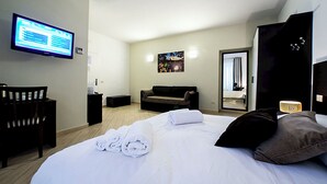 A hotel room with a bed, a desk, a chair, a television, a sofa, a mirror, and a painting on the wall. - A View of Rome (Rome)