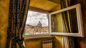 A room with a window overlooking a historic building, curtains, and a radiator. - A View of Rome (Rome)
