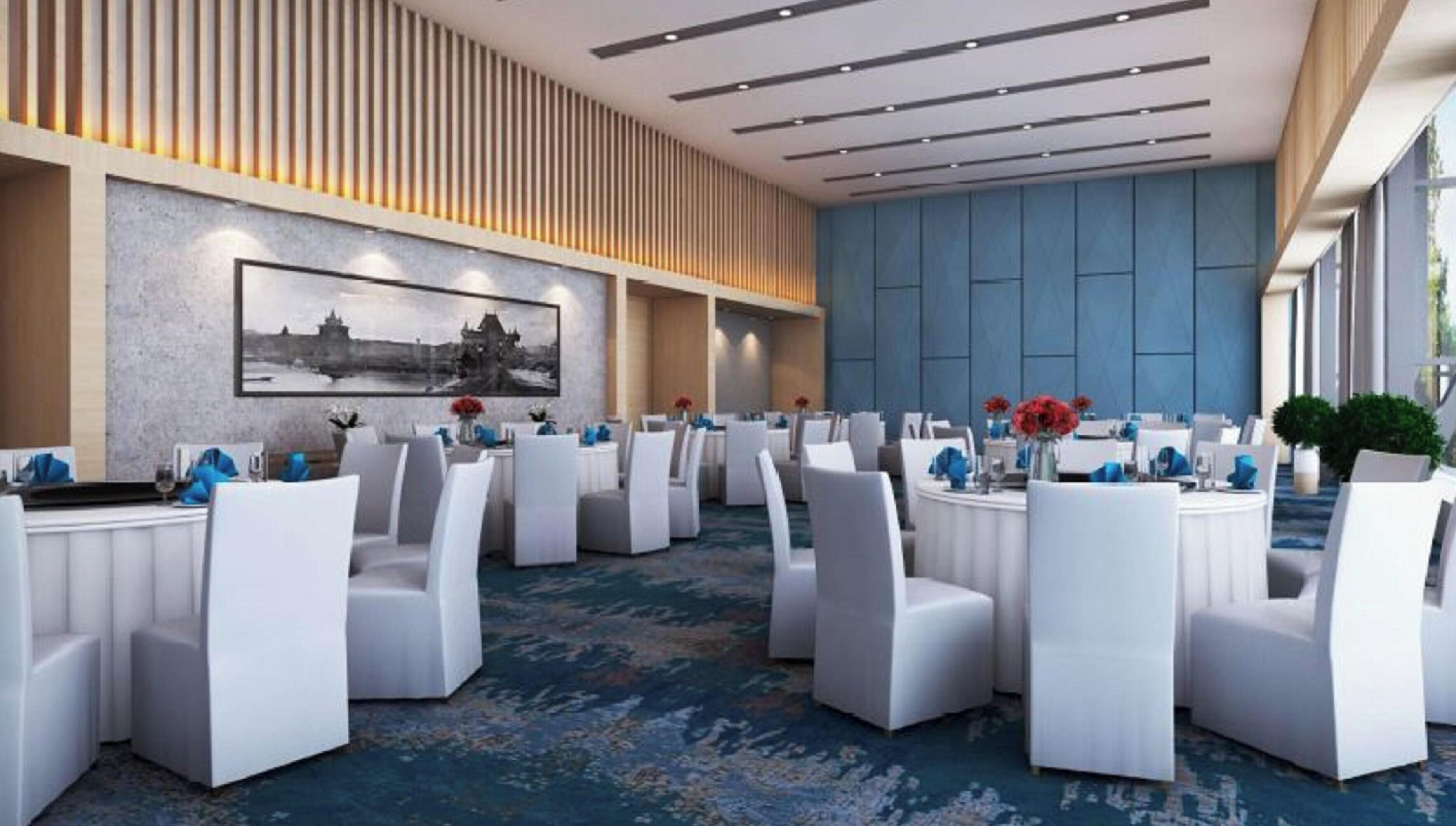 A conference room with white chairs, tables, and a large wall-mounted picture.