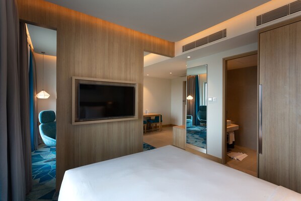 A hotel room with a large bed, a TV mounted on the wall, a desk with chairs, and a bathroom visible through an open door. - Holiday Inn Express & Suites Bengaluru Old Madras Road by IHG (Bengaluru)