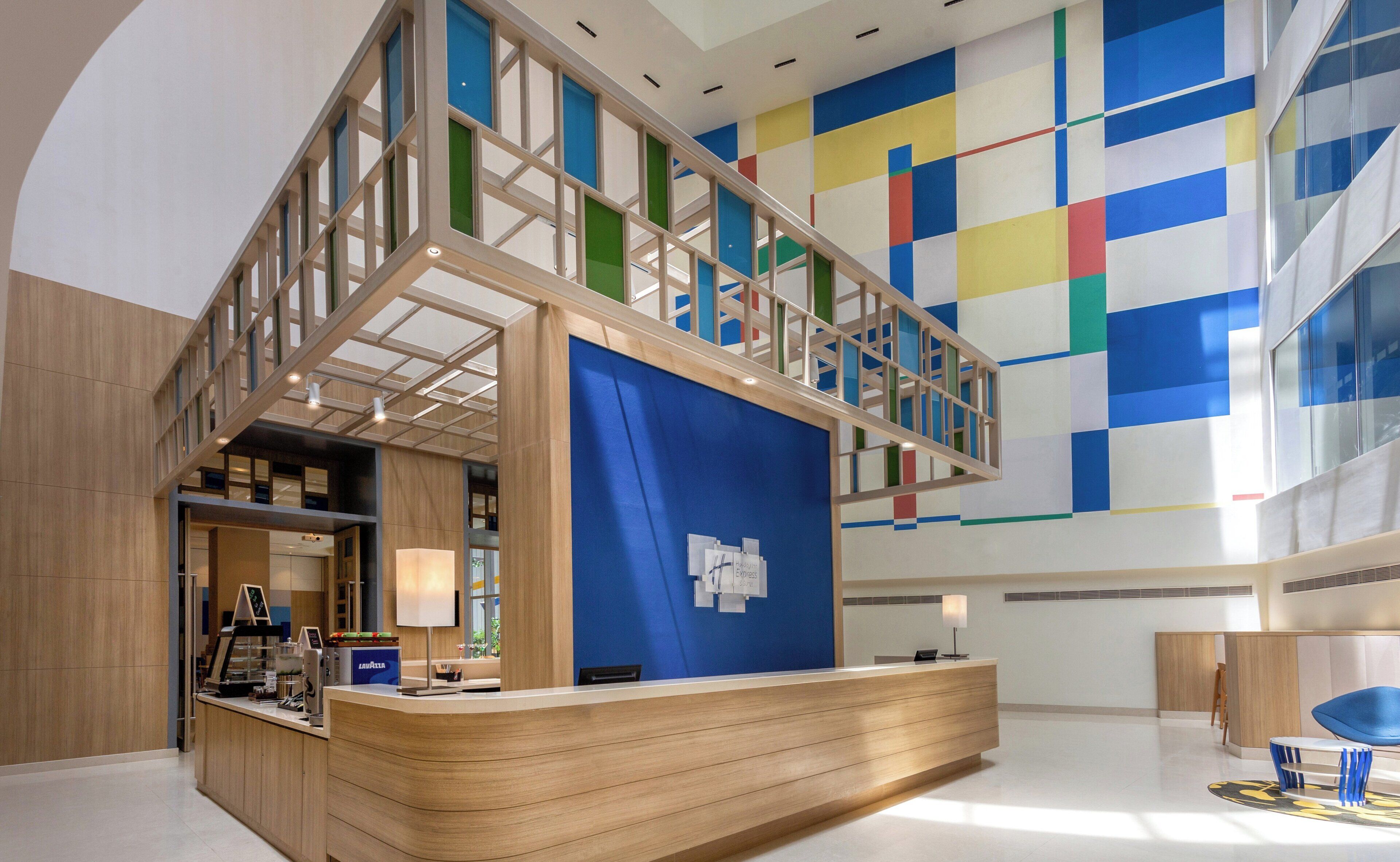 A modern reception area with a wooden reception desk, a blue partition, and a colorful geometric wall design.