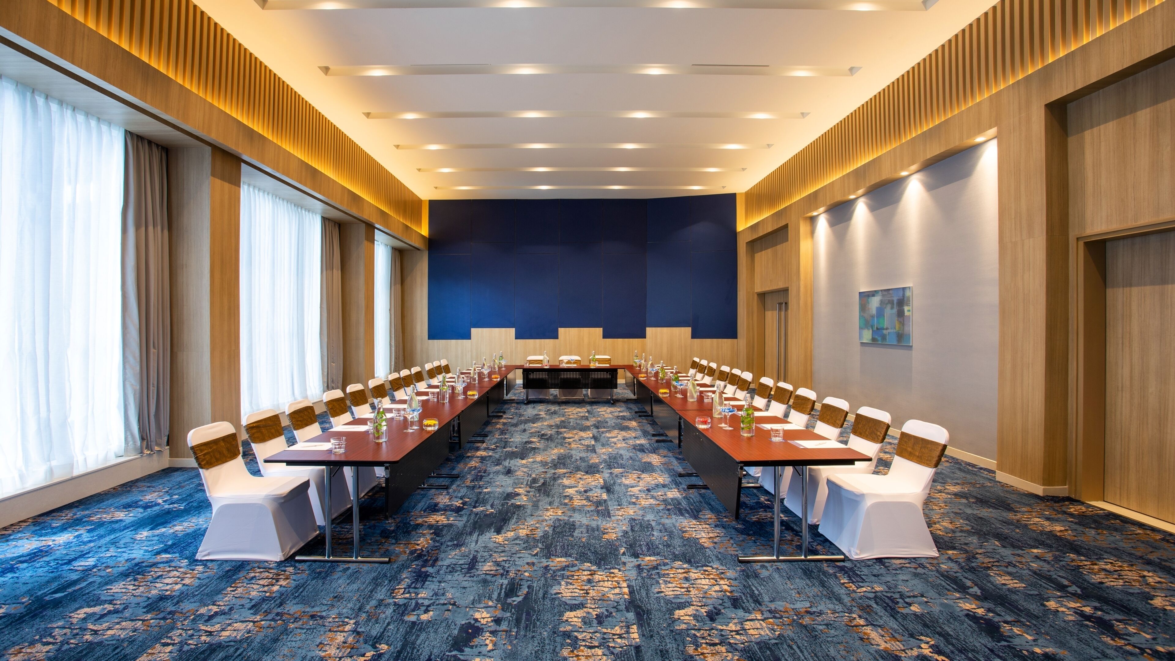 Un salón de conferencias con una larga mesa, sillas y piso alfombrado.