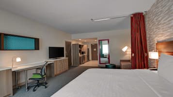 Habitación de hotel con una cama grande, un escritorio con una silla, un televisor y un espejo.