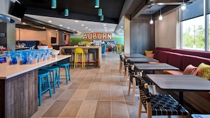A restaurant interior with a long counter, multiple seating options, and a mural of trains on the back wall.