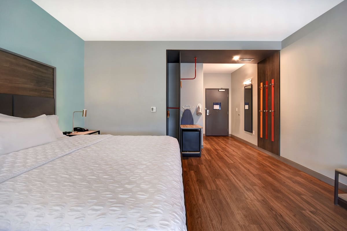 A modern hotel room with a large bed, a small desk, and a seating area.