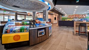 A food counter with a variety of snacks and drinks, a coffee machine, and a sign that says "AUBURN".