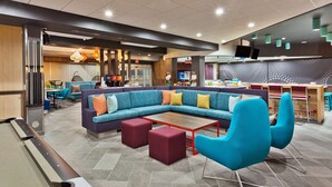 A modern lounge area with a pool table, comfortable seating, and a bar area in the background. - Tru By Hilton Prattville (Prattville)