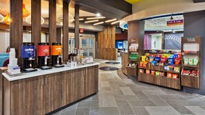 A modern hotel lobby with a coffee station, snack bar, and a reception area. - Tru By Hilton Prattville (Prattville)