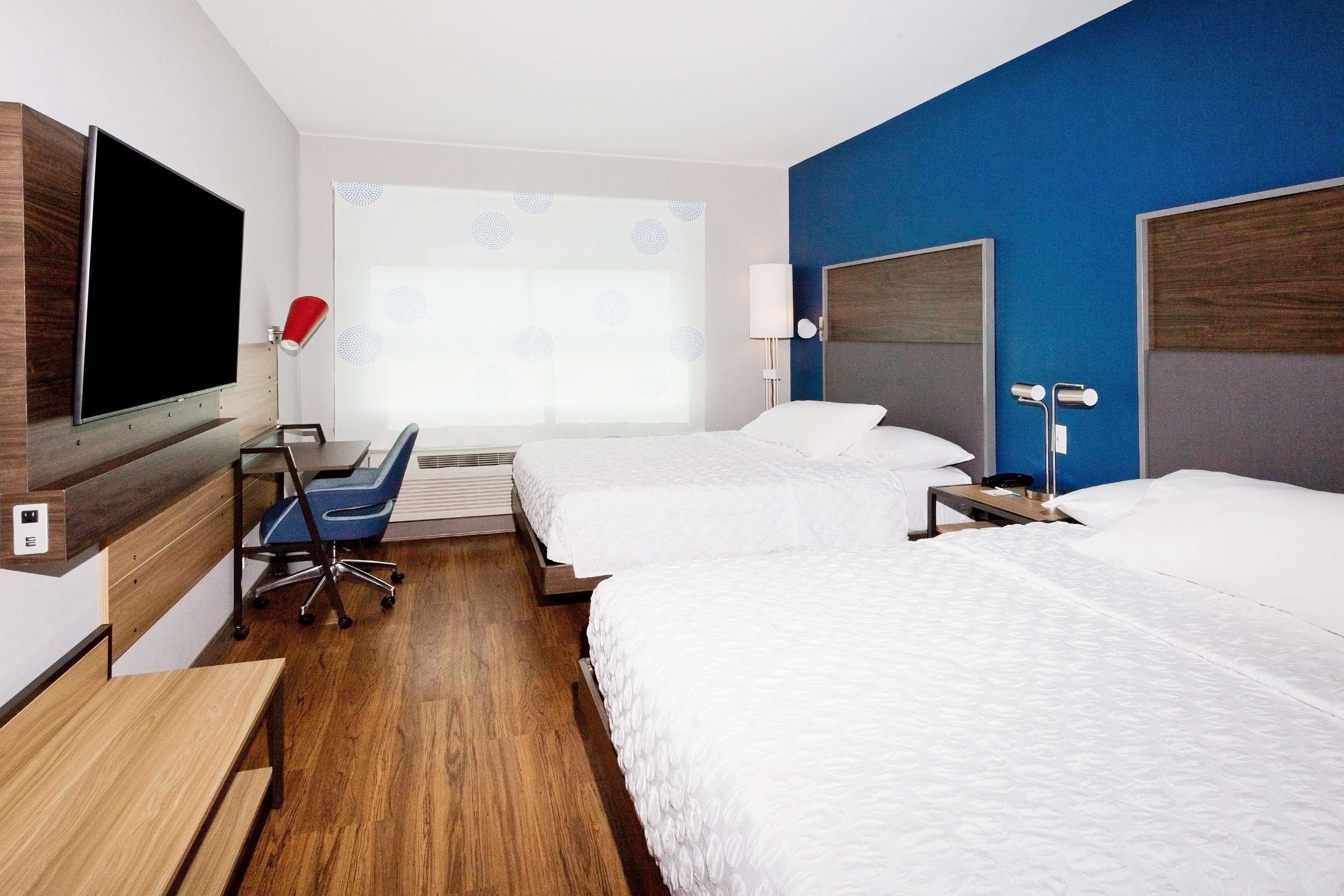 Hotellihuone, jossa on kaksi sänkyä, työpöytä, tuoli, televisio ja ikkuna, josta on näkymä.