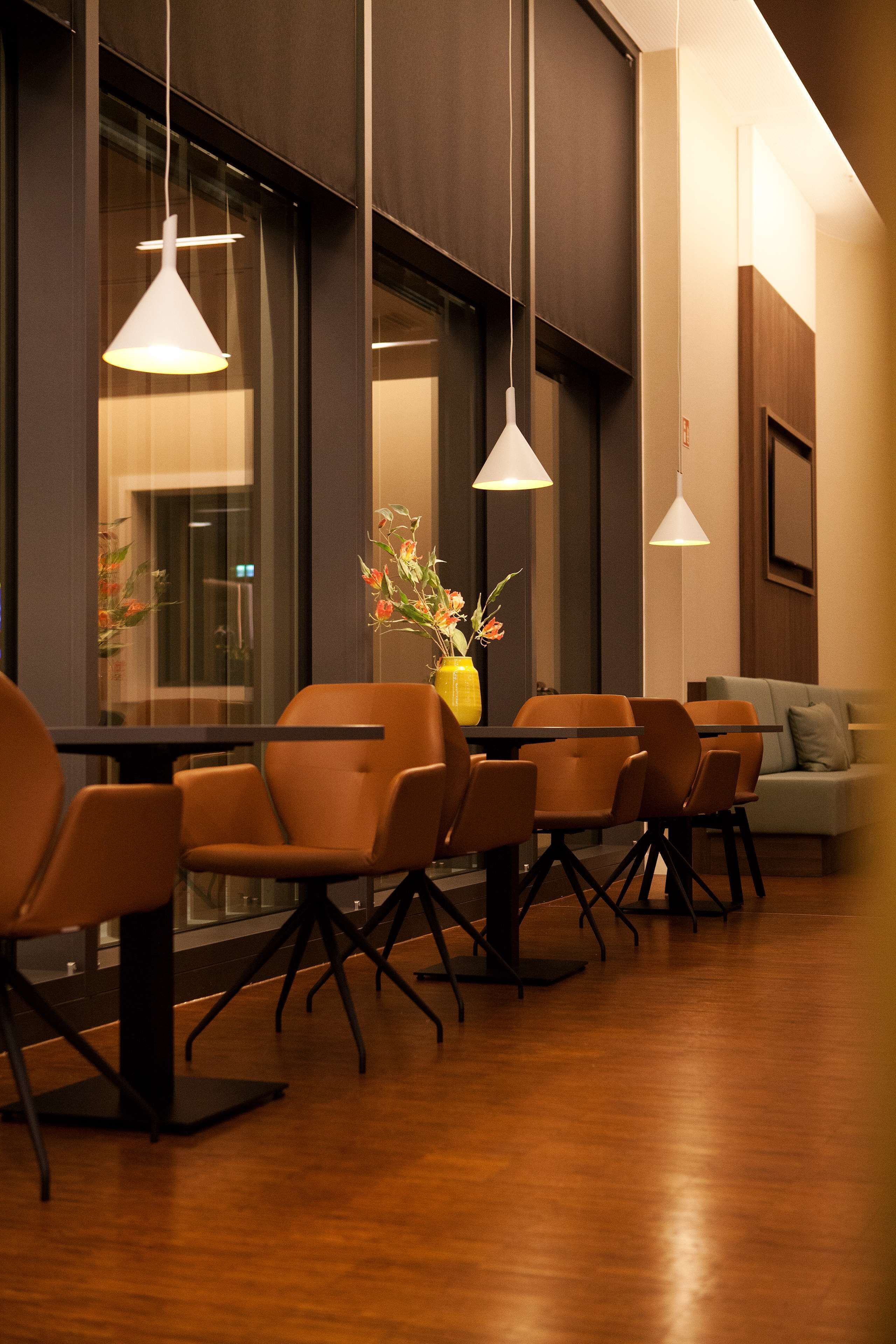 A modern dining area with wooden flooring, a table with chairs, and pendant lighting.