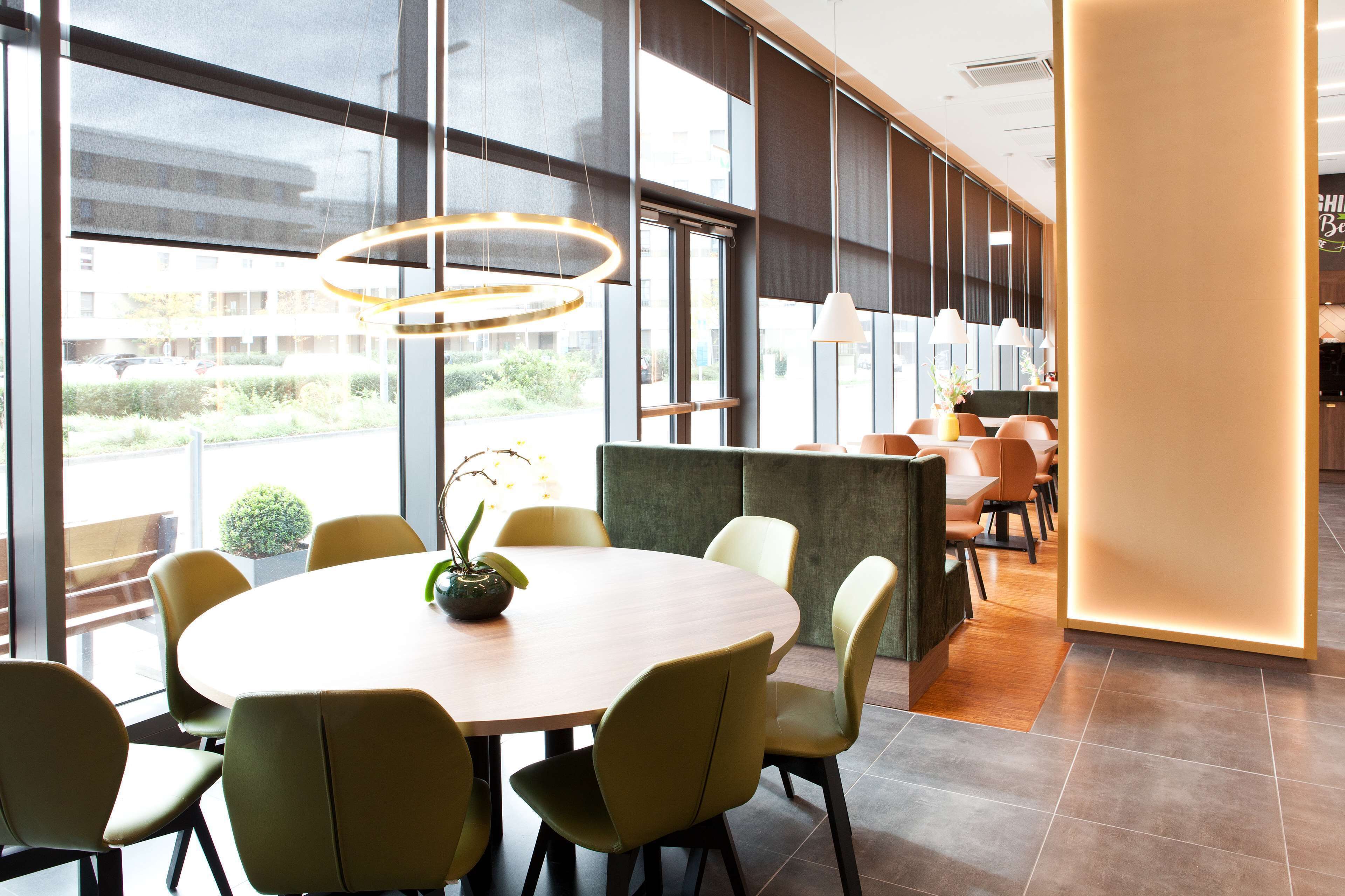 Un comedor moderno con una mesa redonda, sillas verdes y una planta en maceta.