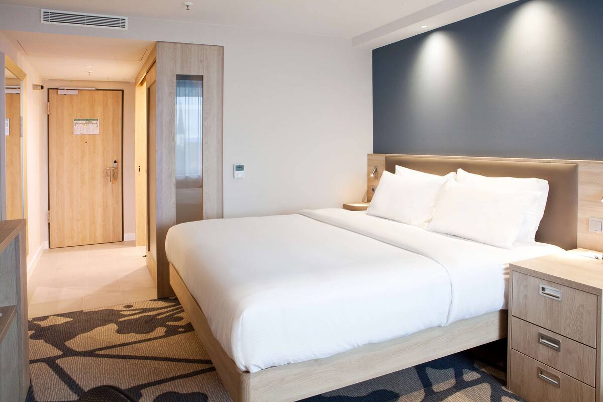 Una habitación de hotel con una cama grande, una mesita de noche y un armario.