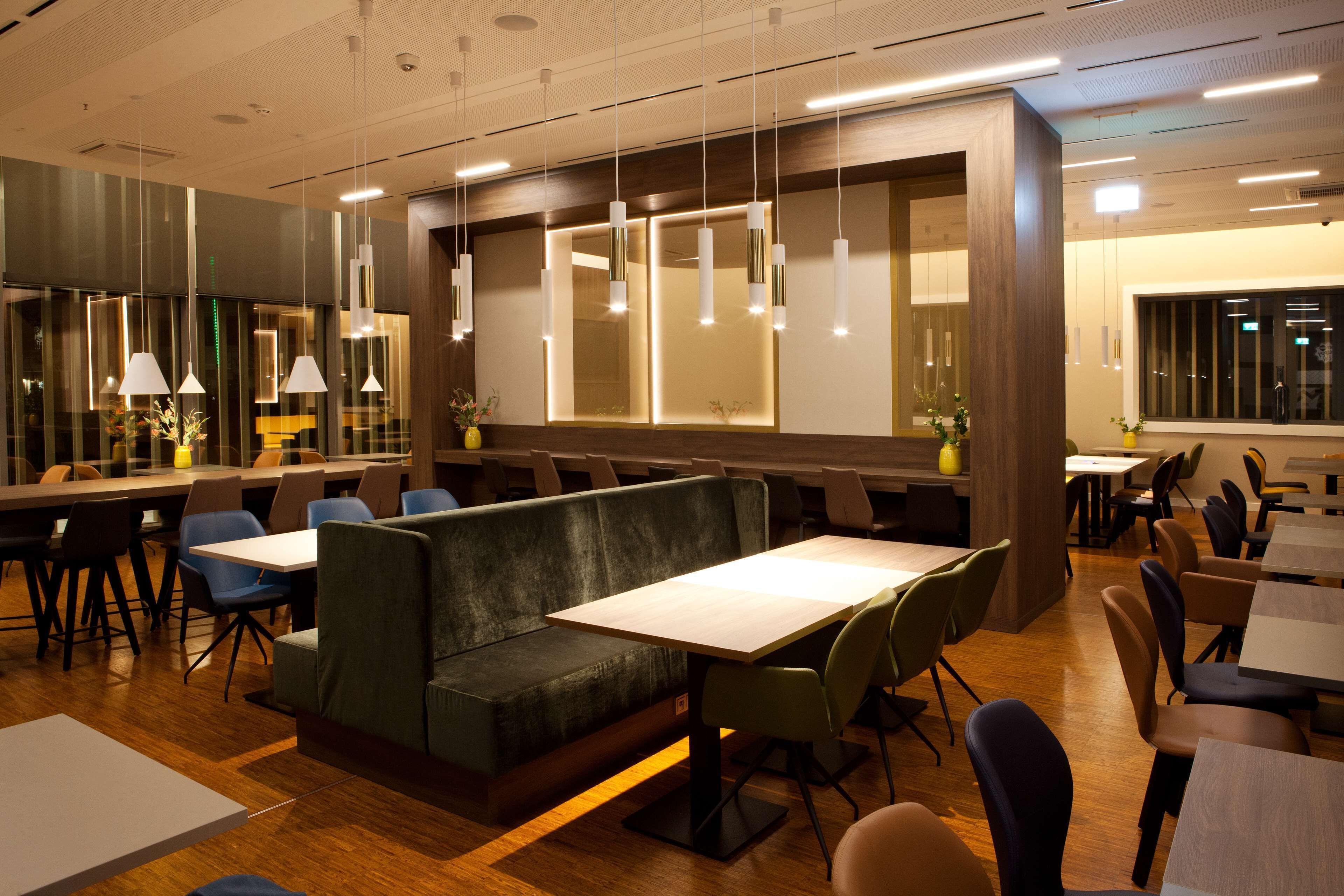 Un restaurant modern amb taules altes, seients a boxes i llums penjants.
