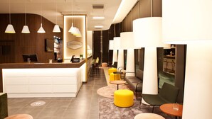 Zona de recepción de un hotel con mostrador, asientos y vista al salón de comidas.