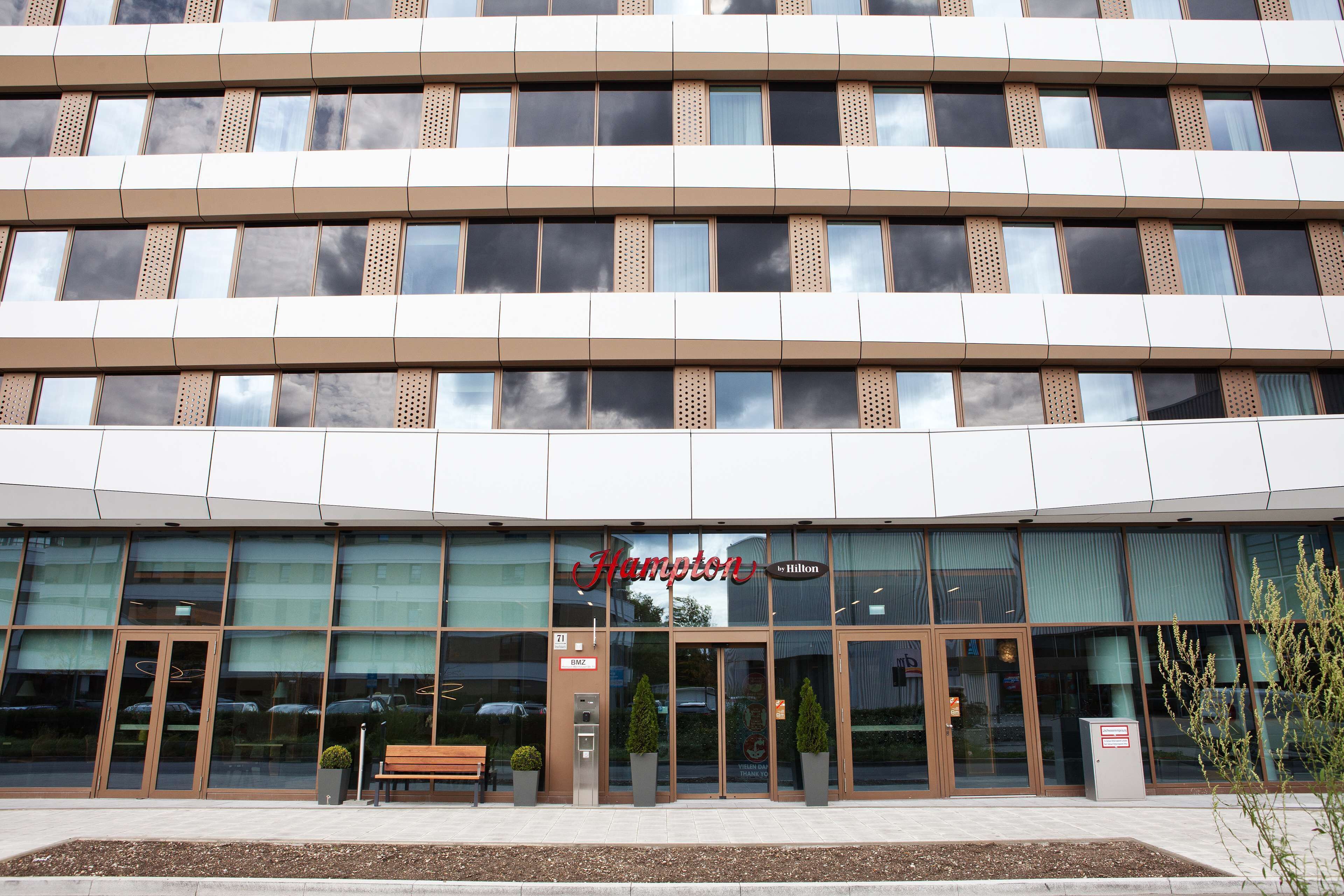 A modern hotel entrance with large glass windows, a prominent brand name, and a well-maintained exterior.